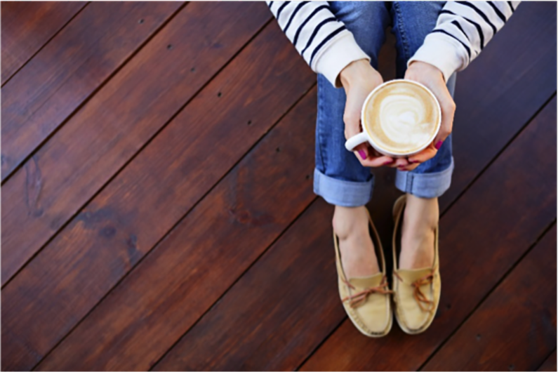 Woman sitting on hardwood floor with cappuccino